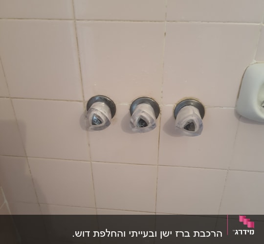 שלושה ברזים על קיר אריחים בחדר אמבטיה